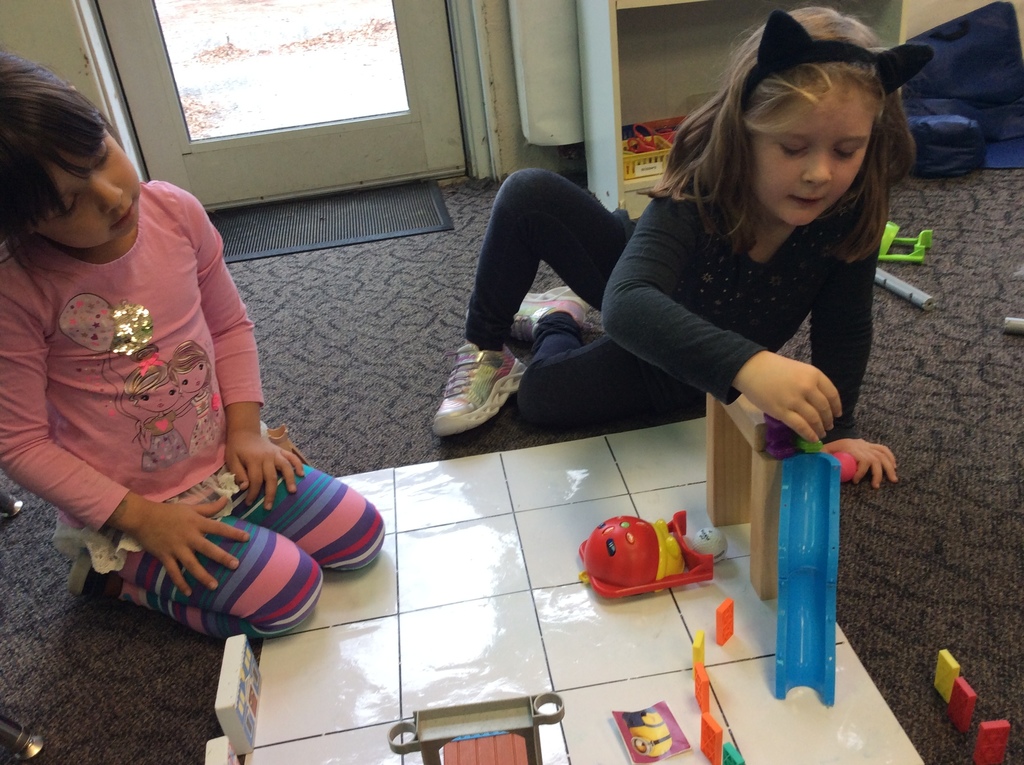 These girls code Bee-Bot to push a ball through the "playground" that they built.